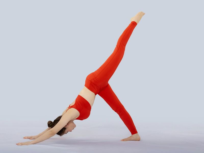 Woman performing a fluid stretching movement in a minimalist, calm studio.